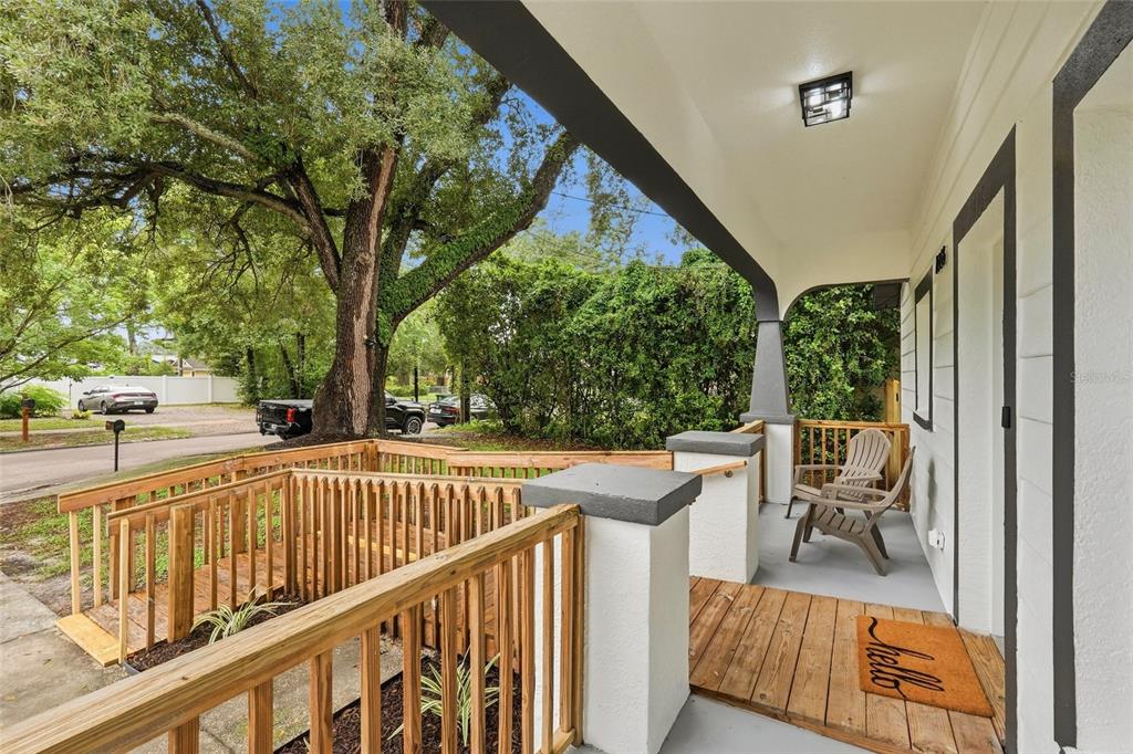 A covered front porch features a wooden ramp, a welcome mat, and a wooden chair — 1316 E GIDDENS AVENUE, TAMPA, FL