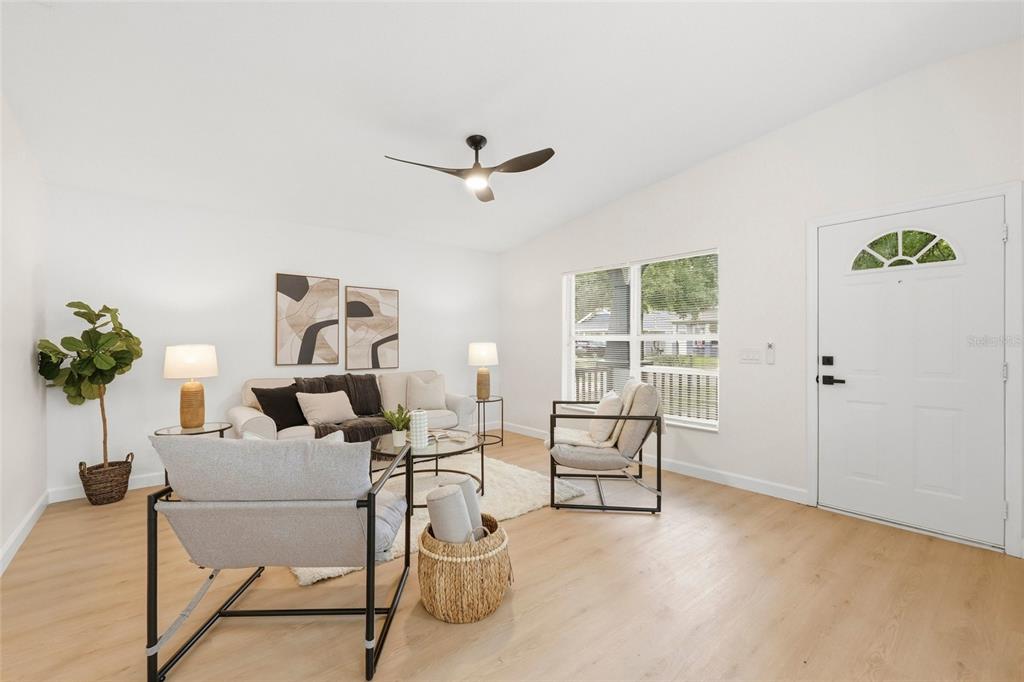 A bright living room features light wood flooring, a ceiling fan, and modern neutral furniture — 1316 E GIDDENS AVENUE, TAMPA, FL