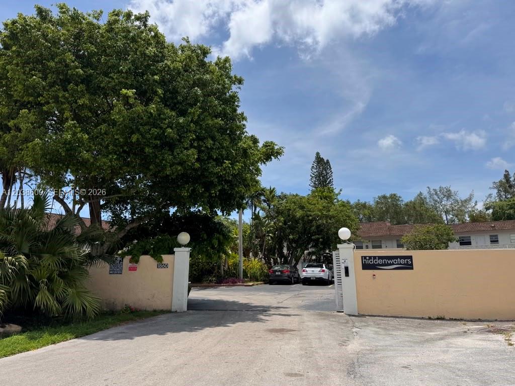 The entrance to the Hiddenwaters complex features a gated driveway flanked by two stucco pillars — 1860 Venice Park Dr # 208, North Miami FL 33181, NORTH MIAMI, FL