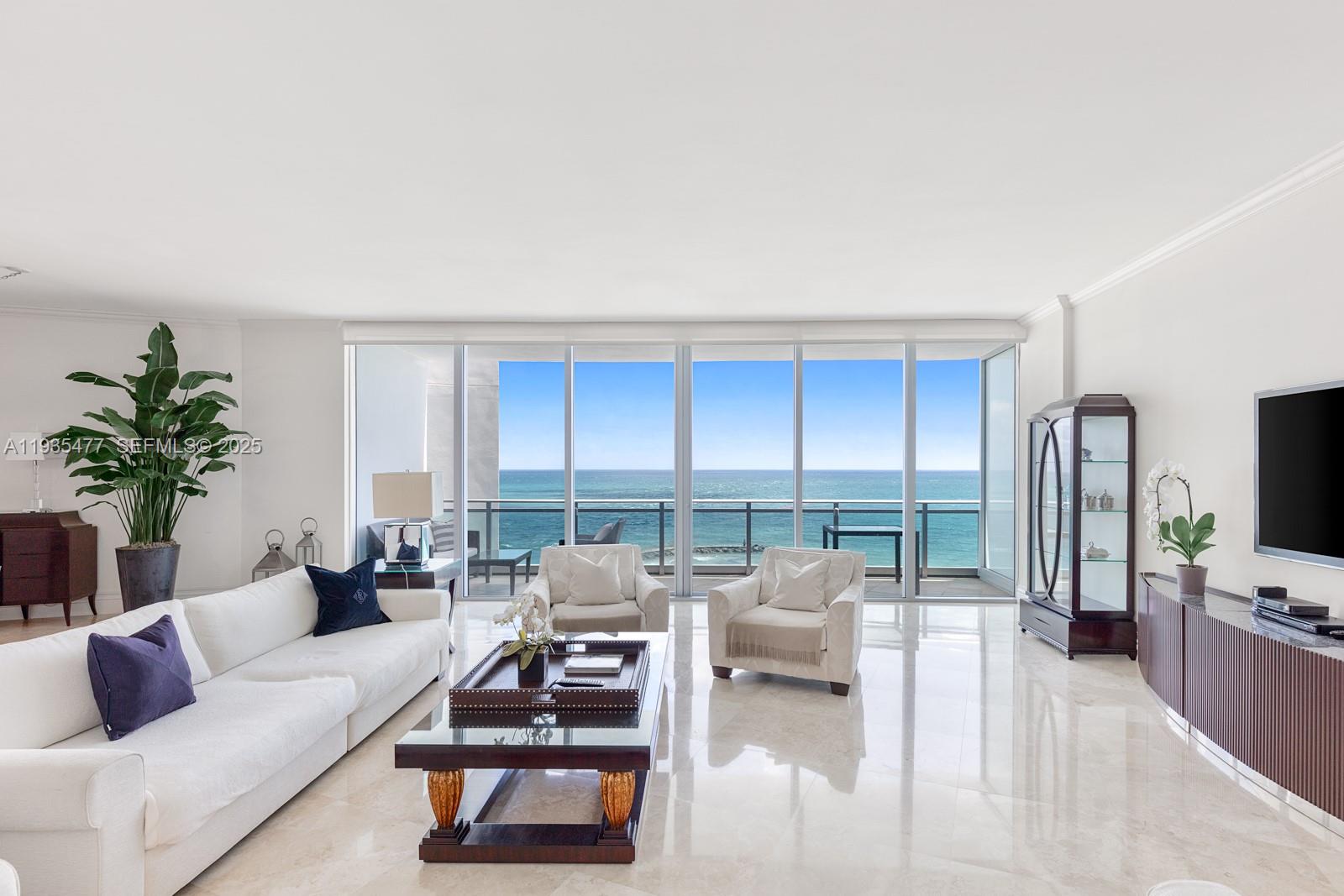 A bright living room features white furniture, marble floors, and floor-to-ceiling windows overlooking the ocean — 10295 Collins Ave # 803, Bal Harbour FL 33154, BAL HARBOUR, FL