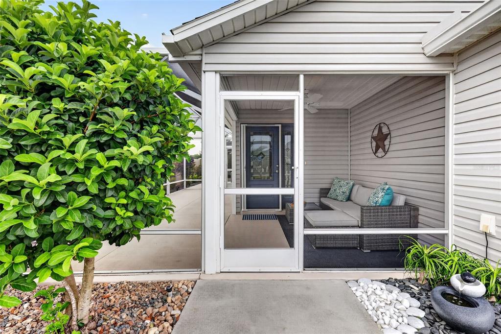 A screened-in patio features a gray sofa, a star wall decoration, and a concrete entrance — 6033 TOMPKINS STREET, THE VILLAGES, FL