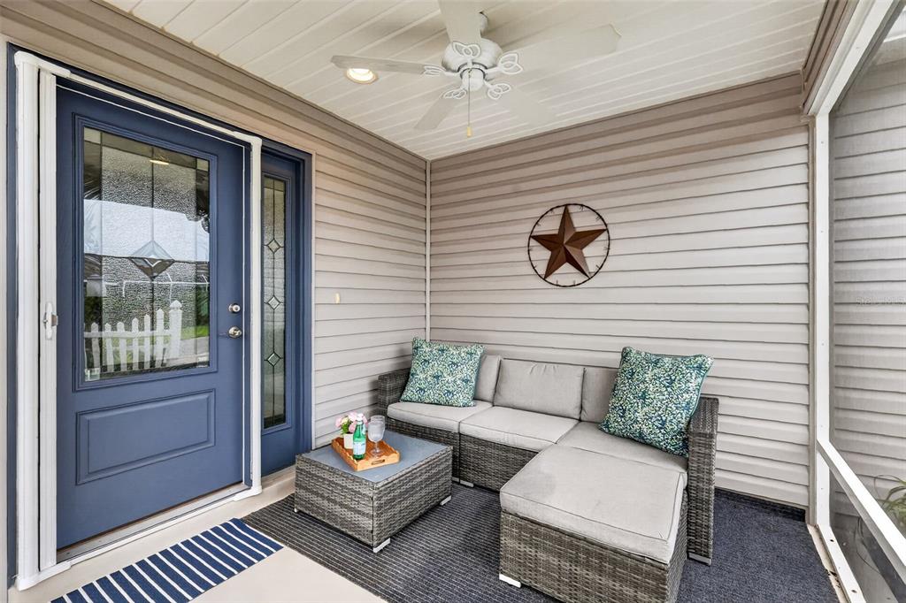 A screened-in porch features a blue door, gray wicker sectional sofa, and a metal star — 6033 TOMPKINS STREET, THE VILLAGES, FL