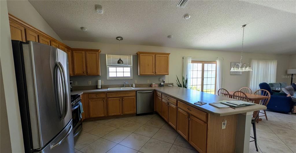 A kitchen with light wood cabinets, stainless steel appliances, and a breakfast bar — 1231 ESTILL AVENUE, THE VILLAGES, FL