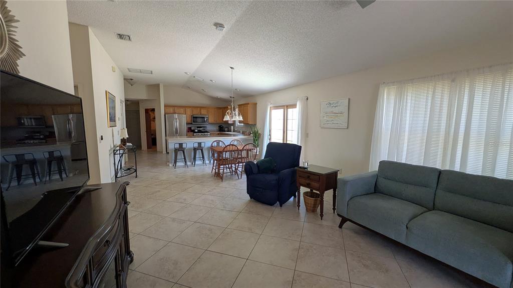 An open-concept living and dining area features tile flooring, a kitchen island, and neutral walls — 1231 ESTILL AVENUE, THE VILLAGES, FL
