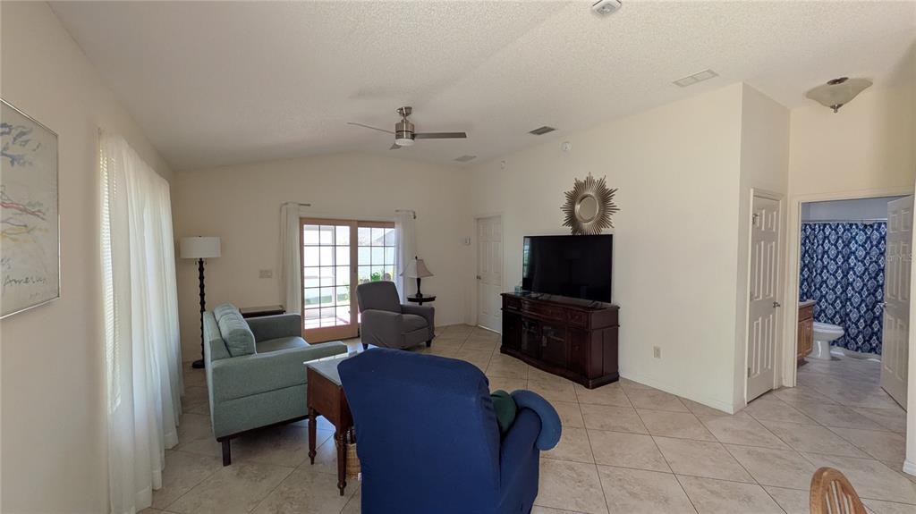 A living room with tile floors, a ceiling fan, a television console, and patio doors — 1231 ESTILL AVENUE, THE VILLAGES, FL