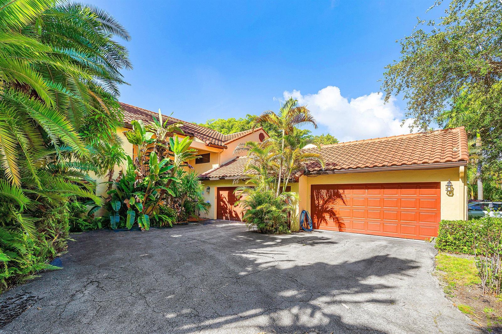 A two-story house with a tile roof, a multi-car garage, and lush tropical landscaping — 16 Via Lago, Boynton Beach FL 33435, BOYNTON BEACH, FL