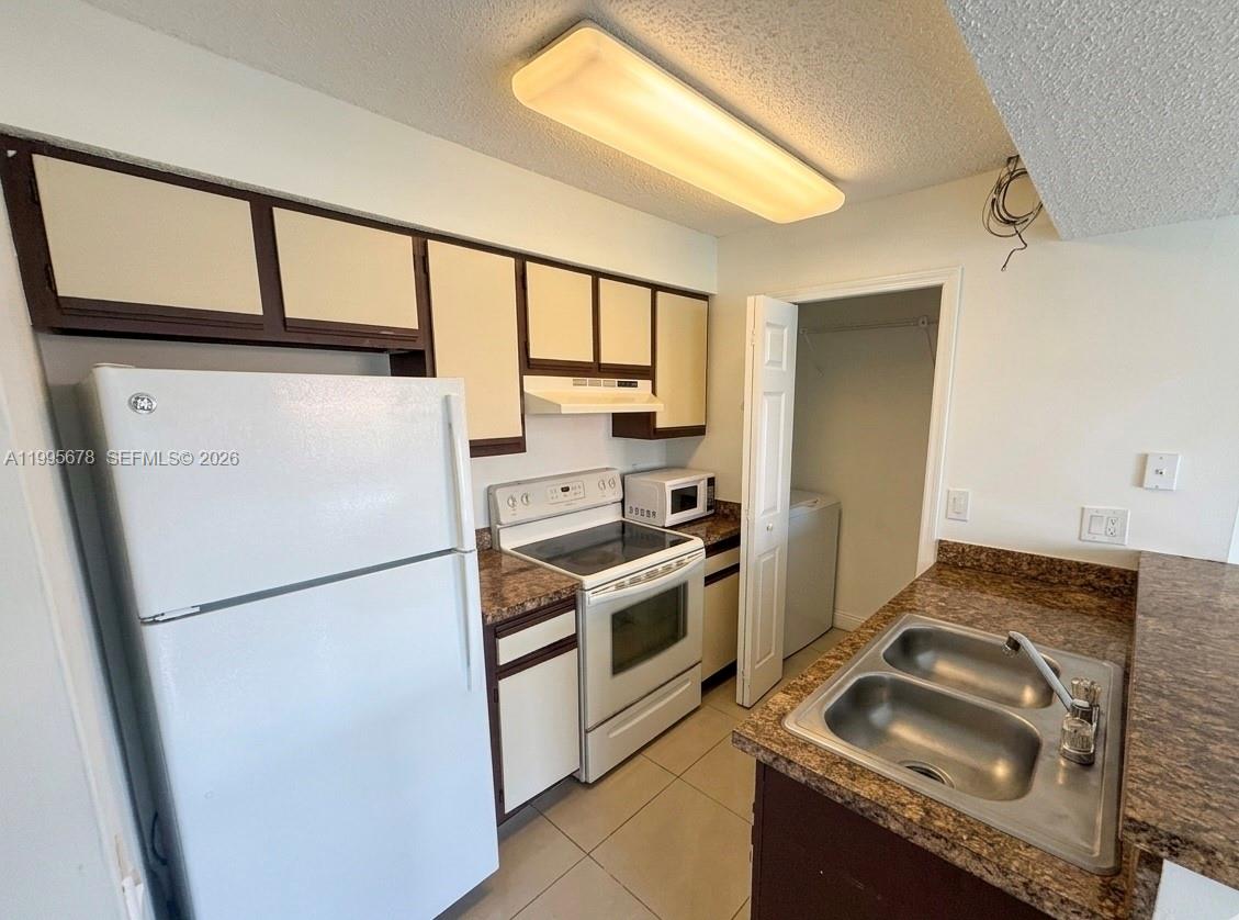 A kitchen features white cabinets, stainless steel appliances, a sink, and light-colored countertops — 1253 SW 46th Ave # 1608, Pompano Beach FL 33069, POMPANO BEACH, FL