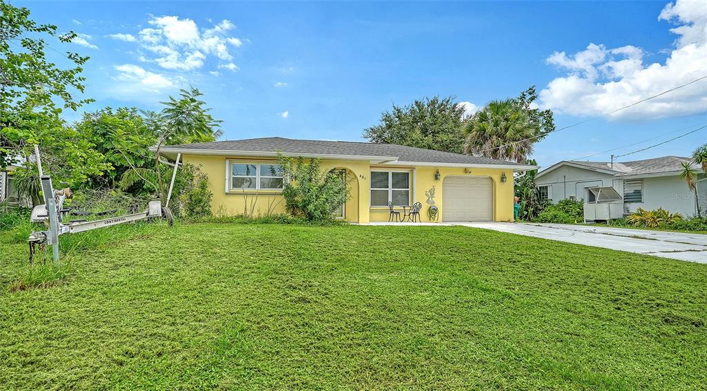 A yellow single-story house with a garage and a boat trailer on the front lawn — 481 W TARPON BOULEVARD NW, PORT CHARLOTTE, FL