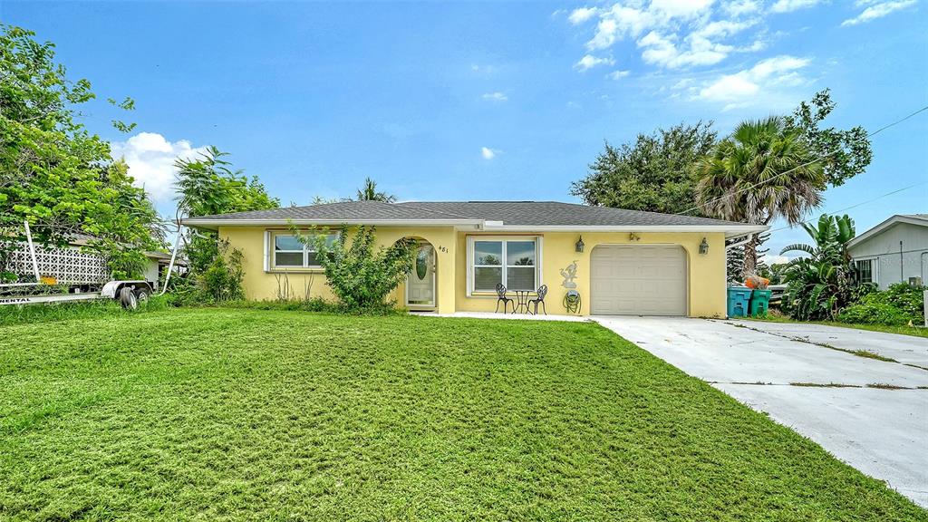 A single-story yellow house with a front lawn, a concrete driveway, and a garage — 481 W TARPON BOULEVARD NW, PORT CHARLOTTE, FL