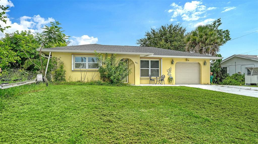 A yellow single-story house with a garage and a large front lawn under a blue sky — 481 W TARPON BOULEVARD NW, PORT CHARLOTTE, FL