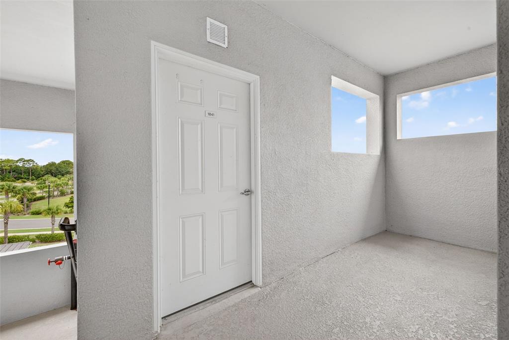 A white door labeled 1841 is set in a textured gray wall on an outdoor balcony — 43997 BOARDWALK LOOP UNIT 1841, PUNTA GORDA, FL