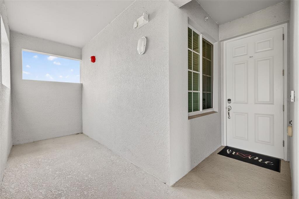 A white front door with a welcome mat sits on a covered concrete porch — 43997 BOARDWALK LOOP UNIT 1841, PUNTA GORDA, FL