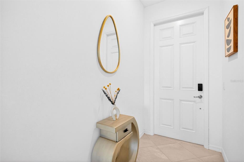 An entryway features a white door, a gold oval mirror, and a modern console table — 43997 BOARDWALK LOOP UNIT 1841, PUNTA GORDA, FL