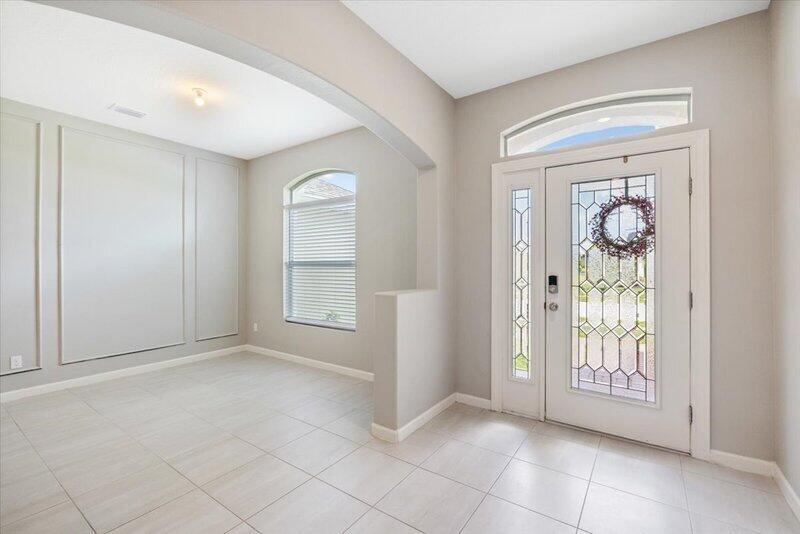 An entryway features light tile flooring, paneled walls, and a white front door with glass — VERO BEACH, FL
