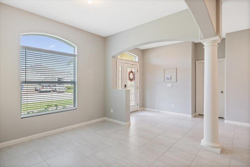 A bright room with light tile flooring, an arched entryway, and a large window — VERO BEACH, FL