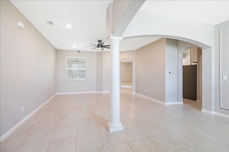 An open-concept living area features light tile flooring, a central white column, and arched entryways — VERO BEACH, FL
