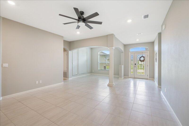 An open-concept living area features light tile flooring, a ceiling fan, and a front entryway — VERO BEACH, FL