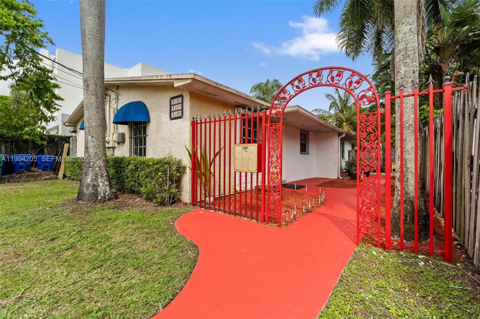 A single-story building features a red metal gate and a matching painted walkway — 3147 Mcdonald St, Miami FL 33133, MIAMI, FL