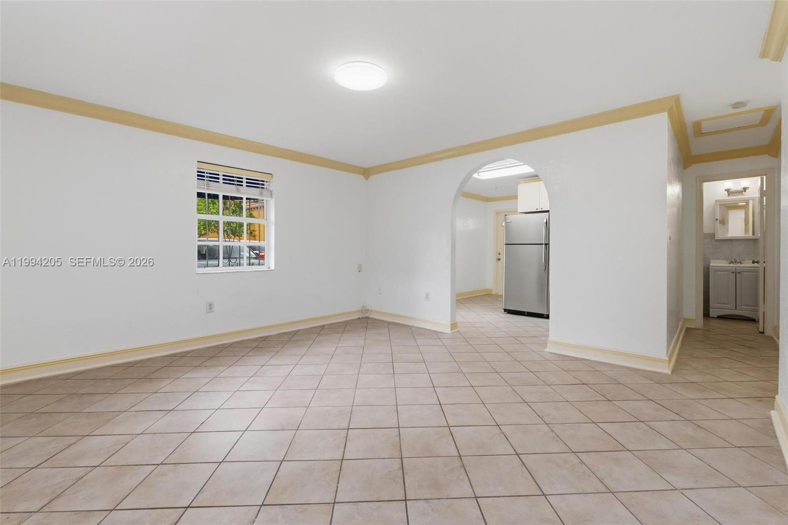A tiled living area features an arched doorway leading to a kitchen and a bathroom — 3147 Mcdonald St, Miami FL 33133, MIAMI, FL