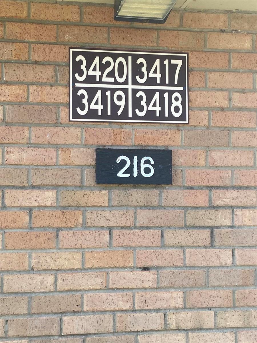 A brick wall displays a sign with four unit numbers above a sign labeled 216 — 3418 34th Way, West Palm Beach FL 33407, WEST PALM BEACH, FL