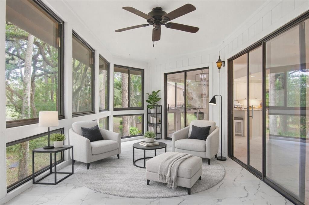 A sunroom with white walls, tile floors, two armchairs, a round rug, and large windows — 20 MASTERS COURT UNIT 20, PALM COAST, FL