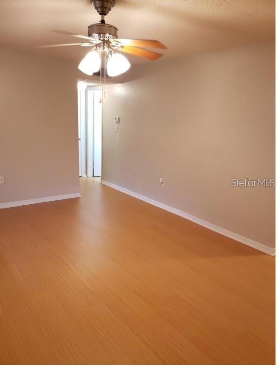 An empty room features light wood-look flooring, beige walls, and a ceiling fan — 700 E AIRPORT BOULEVARD UNIT A5, SANFORD, FL