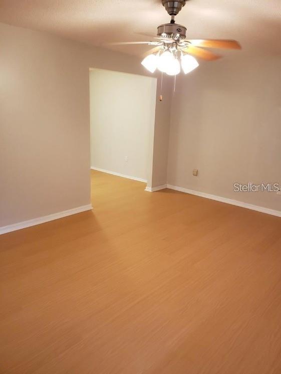 An empty room with light wood-look flooring, gray walls, and a ceiling fan — 700 E AIRPORT BOULEVARD UNIT A5, SANFORD, FL