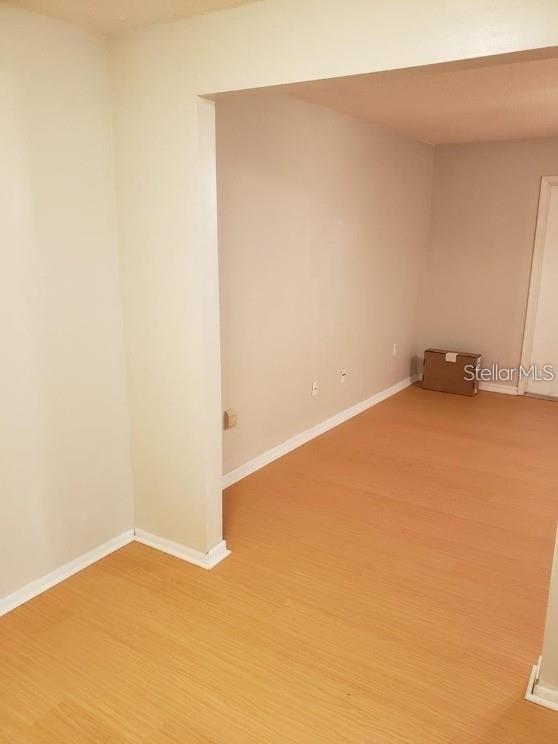 An empty room with light-colored walls and wood-look flooring features a single cardboard box — 700 E AIRPORT BOULEVARD UNIT A5, SANFORD, FL