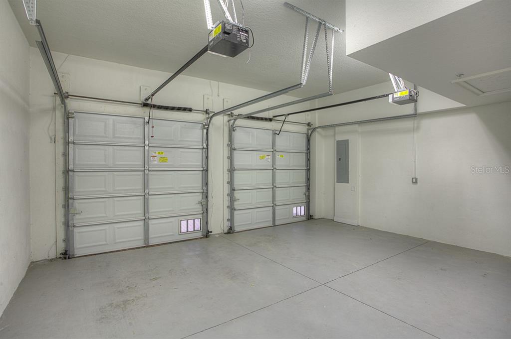 An empty two-car garage with white walls, concrete floors, and two overhead garage doors — 6021 PRINTERY STREET UNIT 106, TAMPA, FL