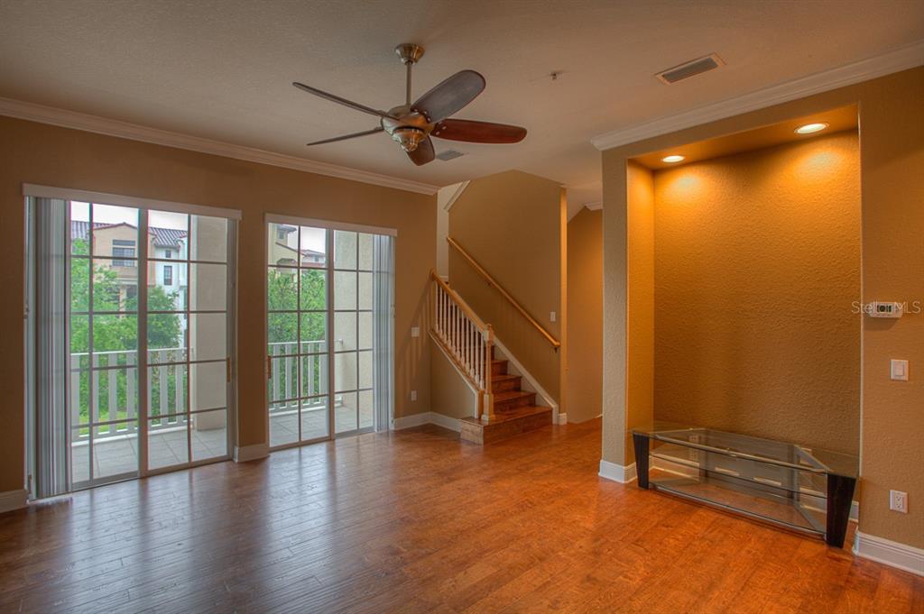 A living room with wood floors, a ceiling fan, a staircase, and a recessed wall niche — 6021 PRINTERY STREET UNIT 106, TAMPA, FL