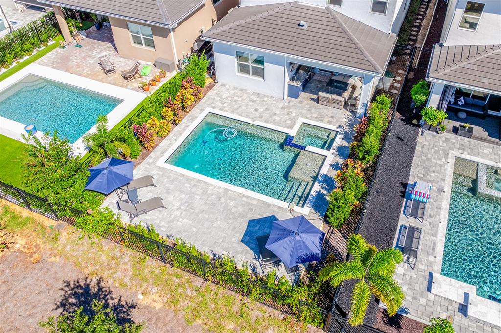 An aerial view shows three adjacent backyards featuring swimming pools, patios, and landscaping — 15714 VETTA DRIVE, BELLA COLLINA, FL