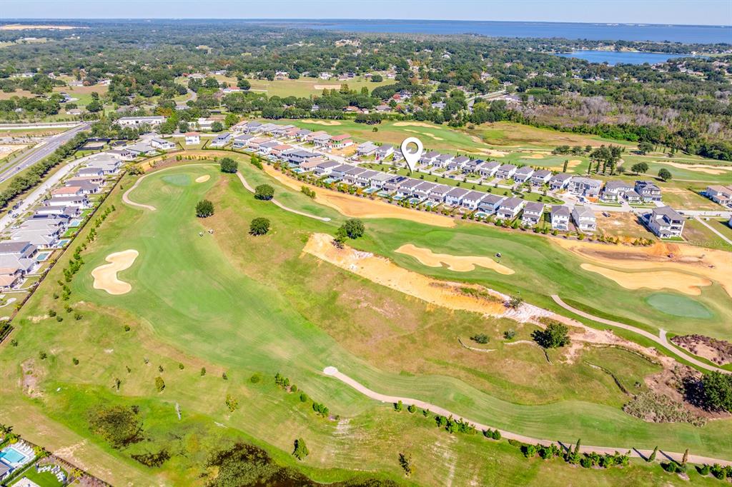 An aerial view shows a residential neighborhood bordering a golf course with sand traps — 15714 VETTA DRIVE, BELLA COLLINA, FL