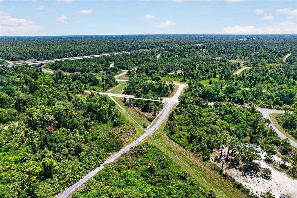 An aerial view shows a triangular plot of land surrounded by trees and paved roads — CUSTER CIRCLE, NORTH PORT, FL
