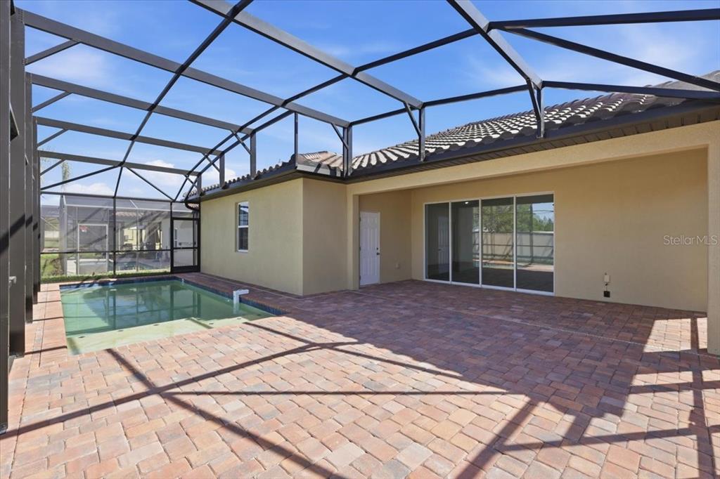 A screened-in patio features a brick paver deck, a swimming pool, and sliding glass doors — 367 VILLA SORRENTO CIRCLE, HAINES CITY, FL