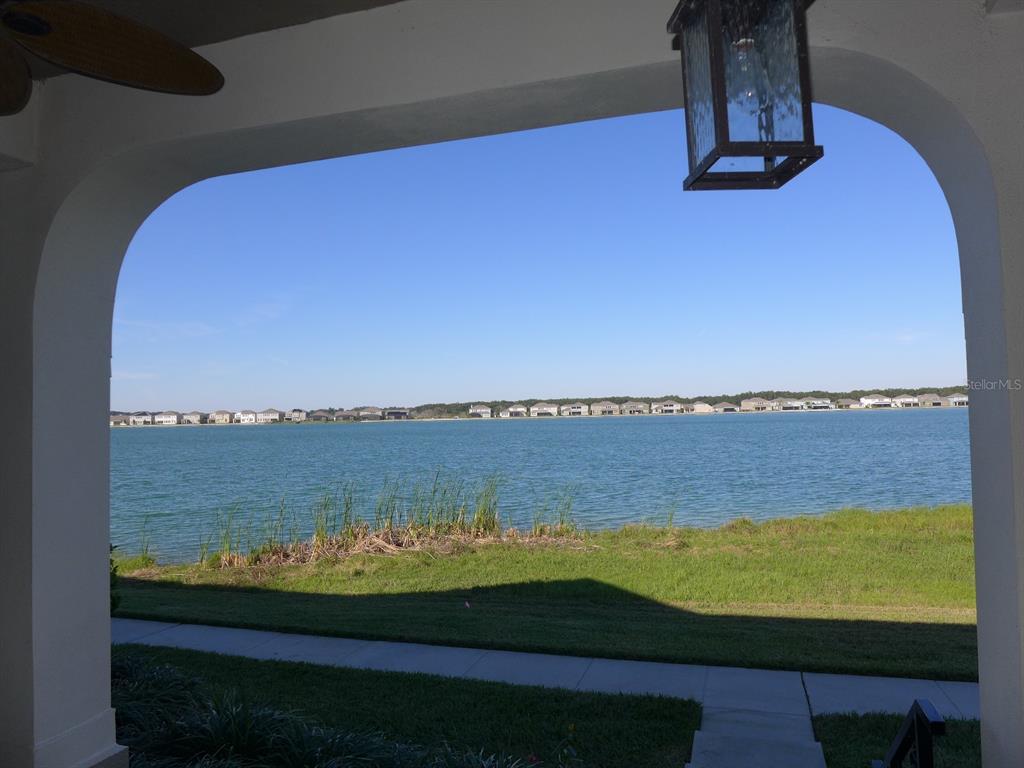 A covered patio overlooks a lake with houses visible on the distant shore — 527 JUNIPER SPRINGS DRIVE, GROVELAND, FL