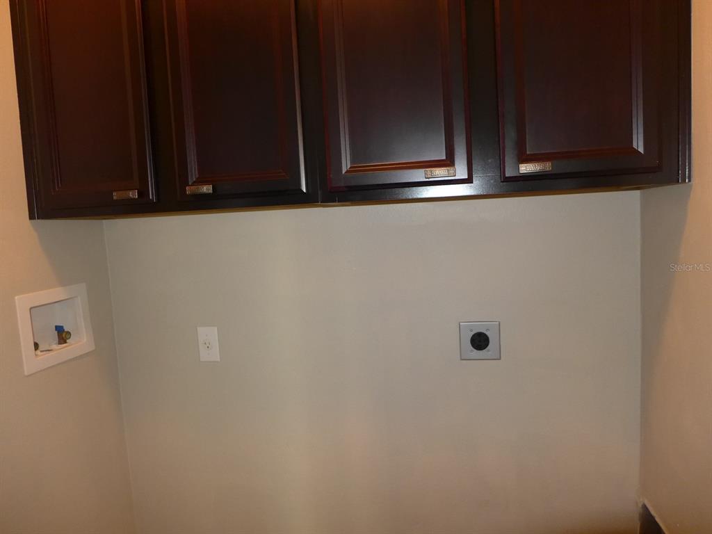 A laundry room features dark wood cabinets mounted above washer and dryer hookups — 527 JUNIPER SPRINGS DRIVE, GROVELAND, FL