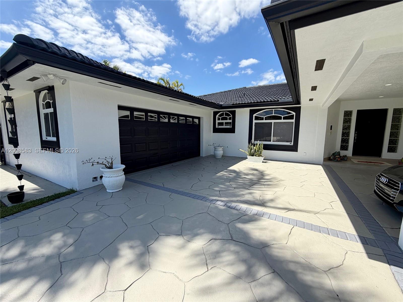 A white house with black trim, a dark tile roof, and a patterned concrete driveway — 13431 SW 32nd St, Miami FL 33175, MIAMI, FL