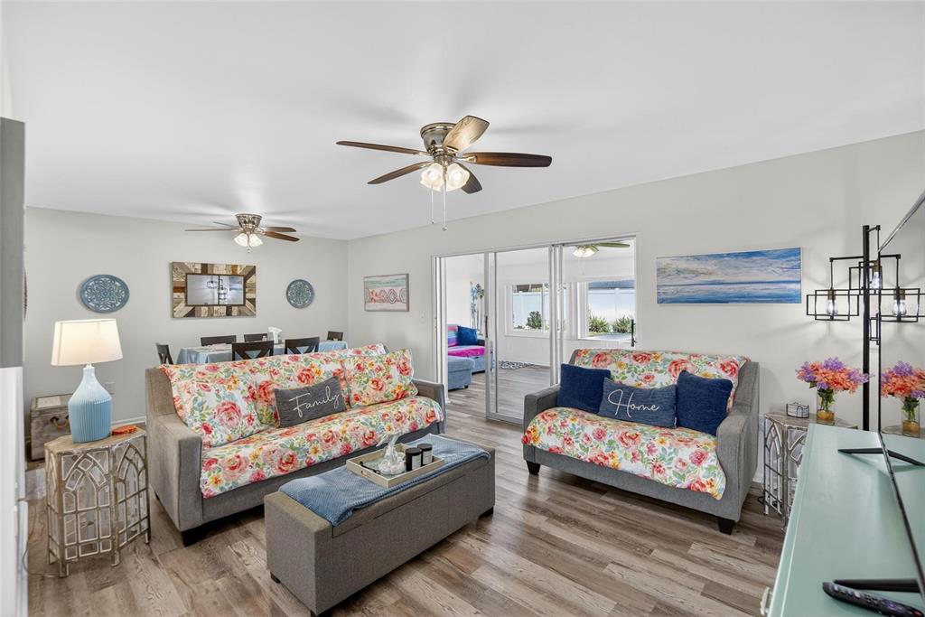 A living room features floral-patterned sofas, wood-look flooring, and a sliding glass door to a patio — 809 OAKMONT AVENUE, SUN CITY CENTER, FL