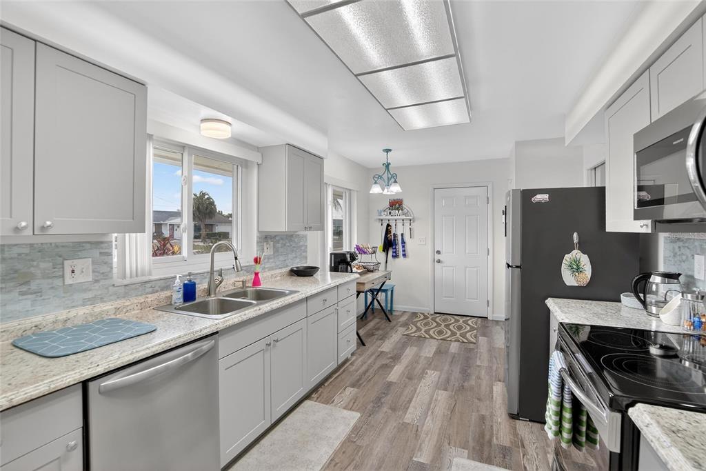 A kitchen features gray cabinets, granite countertops, stainless steel appliances, and wood-look flooring — 809 OAKMONT AVENUE, SUN CITY CENTER, FL