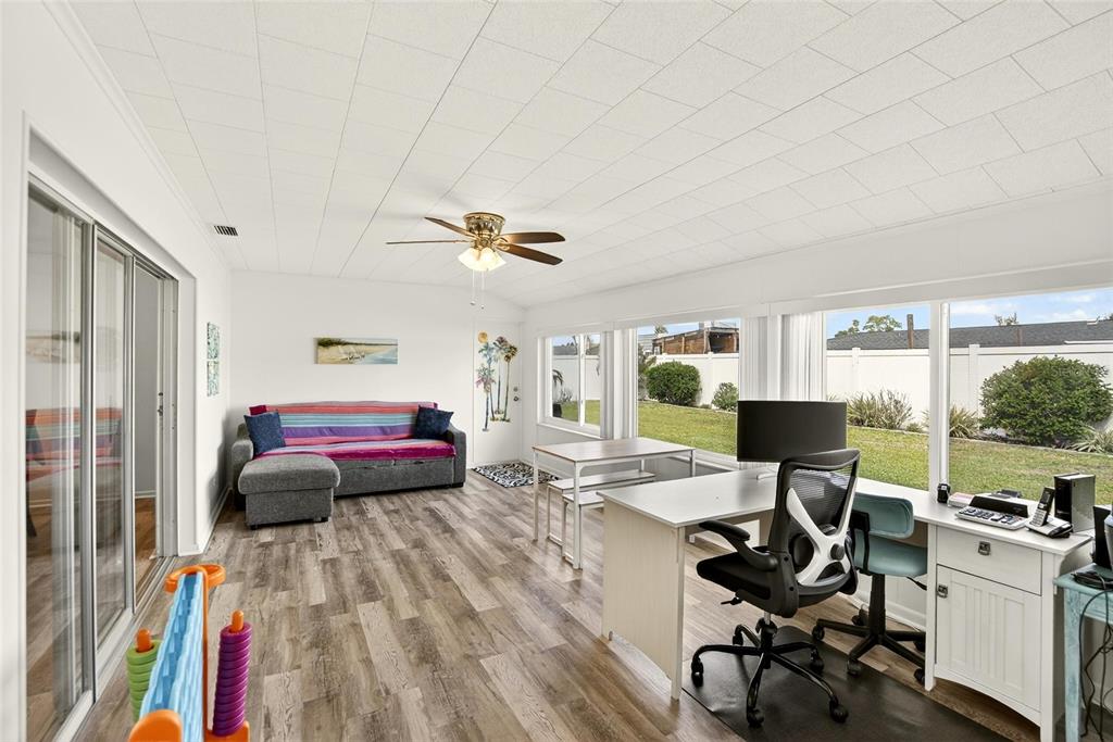 A sunroom features wood-look flooring, a ceiling fan, a sofa, and a desk area — 809 OAKMONT AVENUE, SUN CITY CENTER, FL