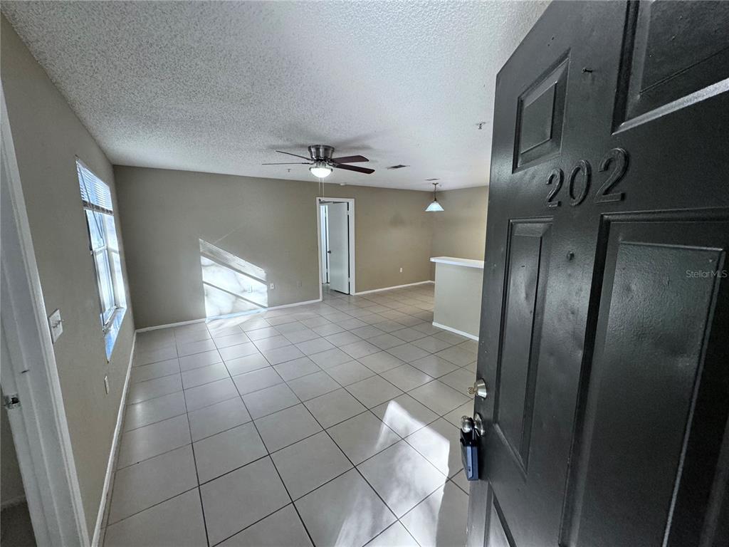 An open-concept living area features light-colored tile flooring, a ceiling fan, and neutral walls — 629 DORY LANE UNIT 202, ALTAMONTE SPRINGS, FL