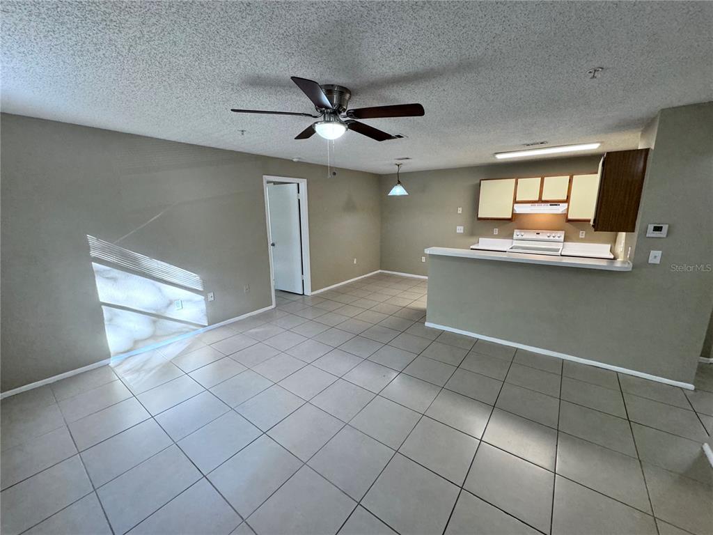 An open-concept living and dining area features tile flooring, a ceiling fan, and a kitchen — 629 DORY LANE UNIT 202, ALTAMONTE SPRINGS, FL
