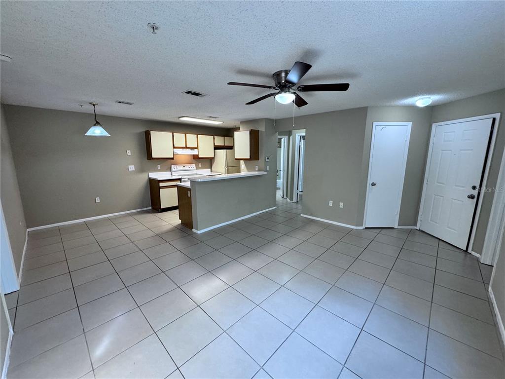 An open-concept kitchen and living area features light-colored tile flooring and a ceiling fan — 629 DORY LANE UNIT 202, ALTAMONTE SPRINGS, FL