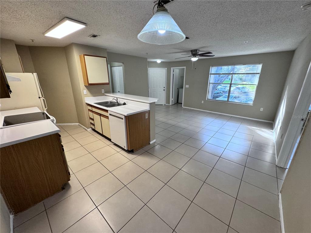 An open-concept kitchen and living area features tile flooring, wood cabinets, and a ceiling fan — 629 DORY LANE UNIT 202, ALTAMONTE SPRINGS, FL
