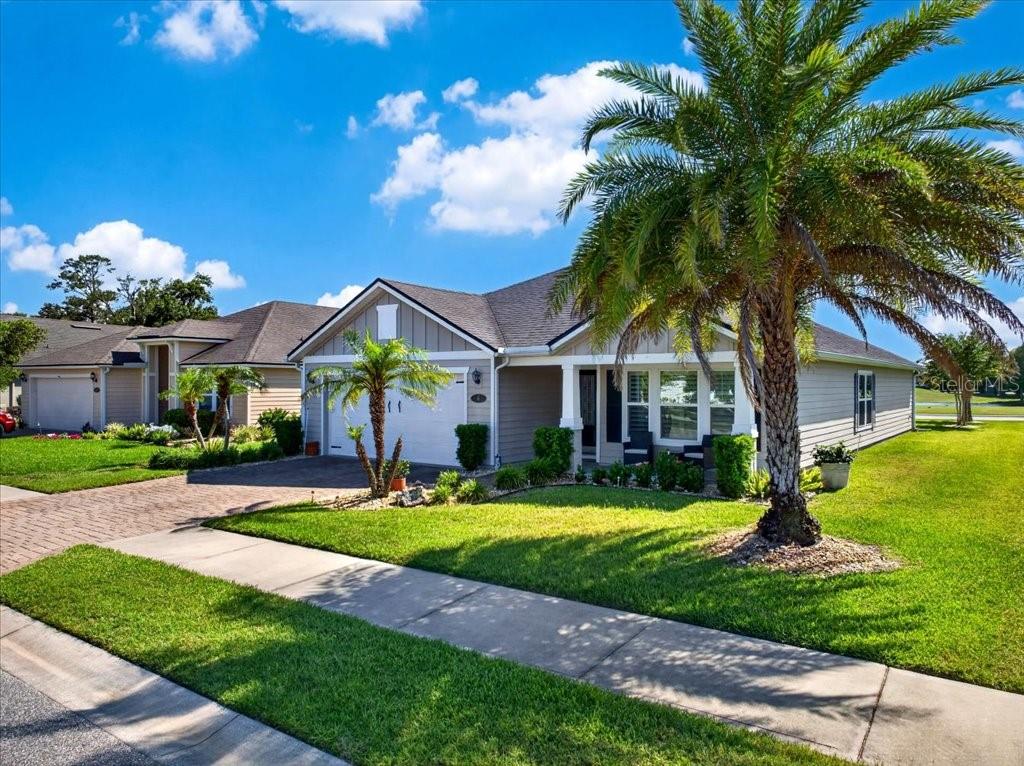 A single-story suburban house with a palm tree in the front yard under a blue sky — 6 COUNTRY CLUB HARBOR CIRCLE, PALM COAST, FL