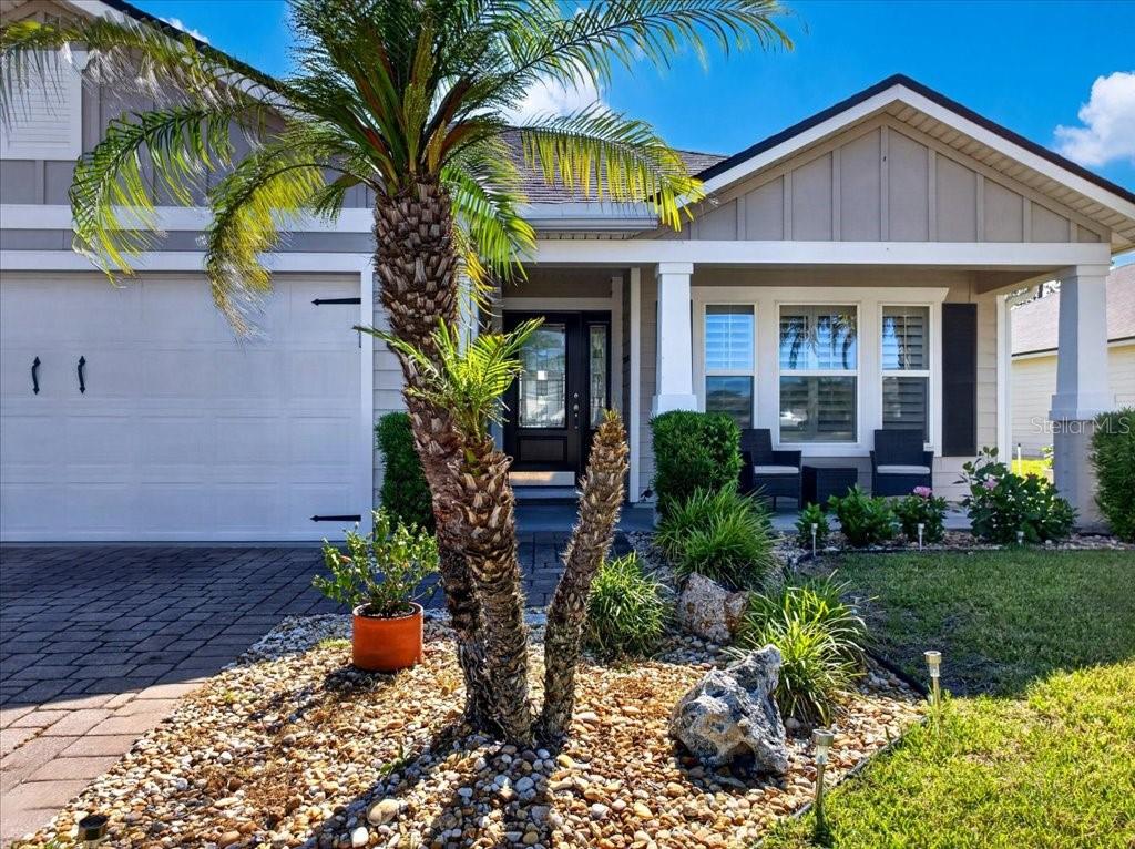 A single-story house exterior features a palm tree, a paved driveway, and a covered porch — 6 COUNTRY CLUB HARBOR CIRCLE, PALM COAST, FL