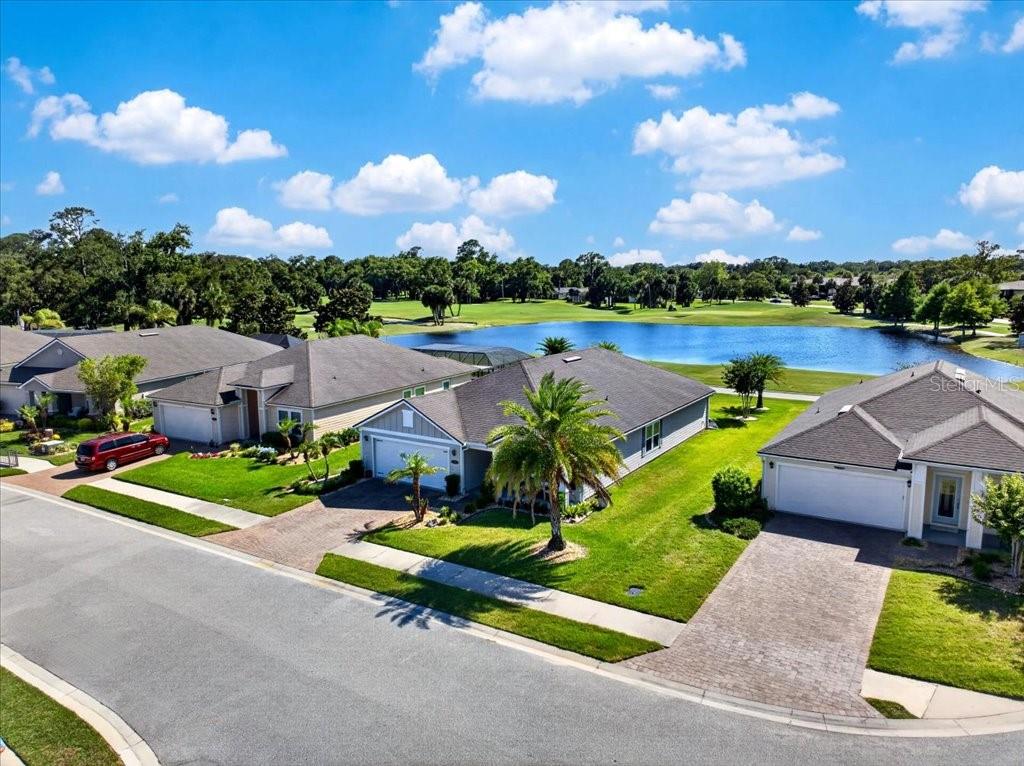 An aerial view of suburban houses with paved driveways overlooking a lake and golf course — 6 COUNTRY CLUB HARBOR CIRCLE, PALM COAST, FL