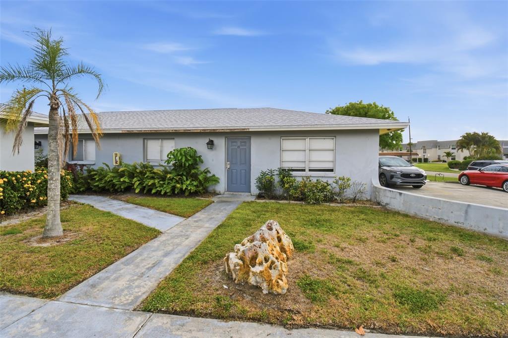 A single-story gray house with a blue front door, a palm tree, and a rock — 4015 SE 19TH AVENUE UNIT 5-9, CAPE CORAL, FL