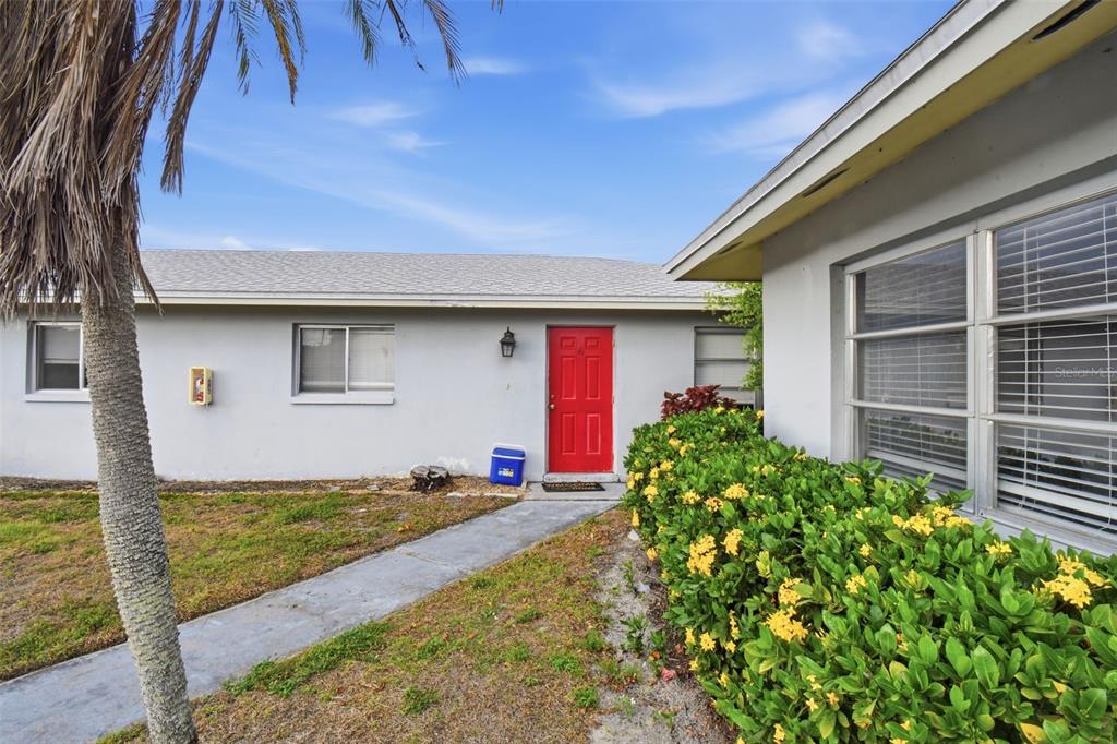 A single-story house exterior features a bright red front door and a concrete walkway — 4015 SE 19TH AVENUE UNIT 5-9, CAPE CORAL, FL
