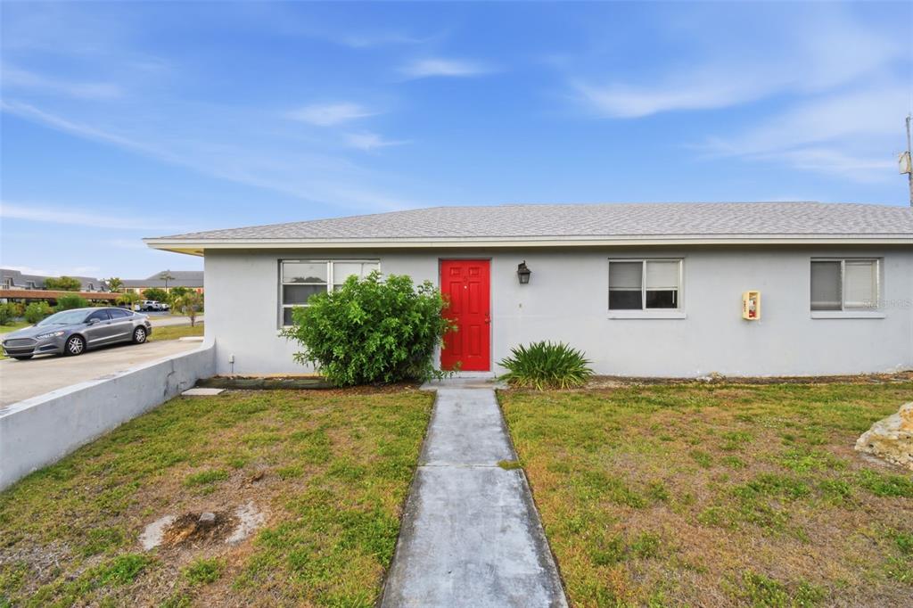 A single-story house with a grey exterior, a red front door, and a concrete walkway — 4015 SE 19TH AVENUE UNIT 5-9, CAPE CORAL, FL